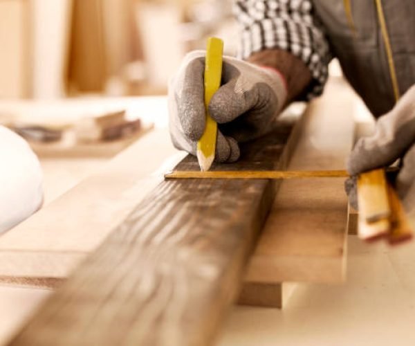 Senior carpenter taking measurement in his workshop